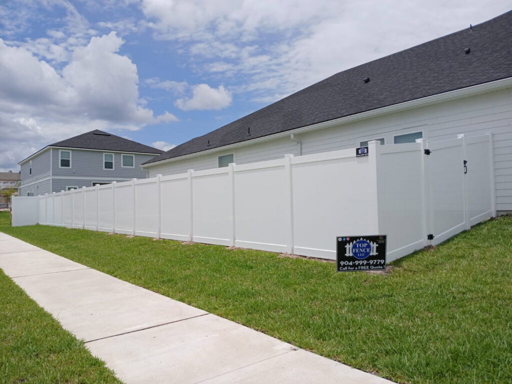 A long white vinyl privacy fence installed along a sidewalk by Top Fence LLC in Jacksonville, FL.