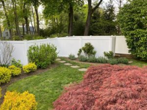 A newly installed white vinyl privacy fence enhancing a beautifully landscaped backyard by AVA Fence & Railing LLC in Stamford, CT.