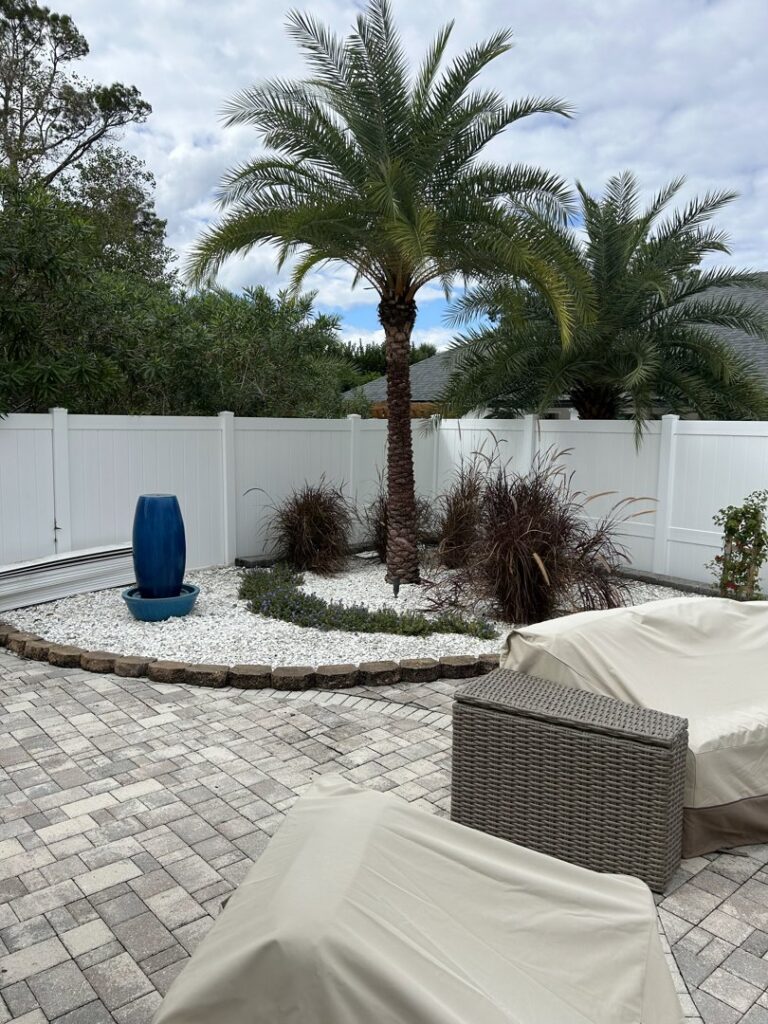 A pristine white vinyl privacy fence enhancing a beautifully landscaped backyard by Fence Nation LLC in Jacksonville, FL.
