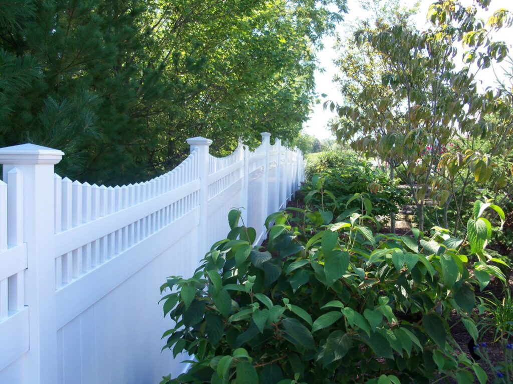 A white vinyl privacy fence complementing backyard landscaping by White Eagle Fence Inc in New Haven, CT.