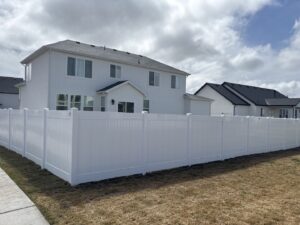 A white vinyl privacy fence installed around a new residential home by Sublime Fencing LLC in North Logan, UT.