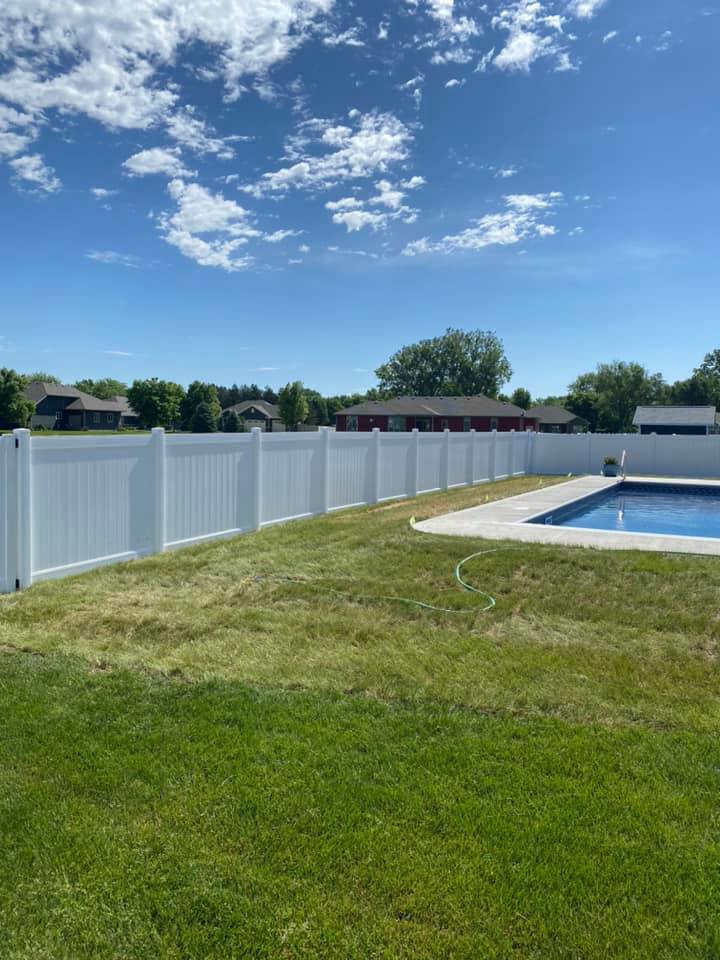 A white vinyl privacy fence installed around a backyard swimming pool by Bostwick Fencing, LLC in Sioux City, IA.