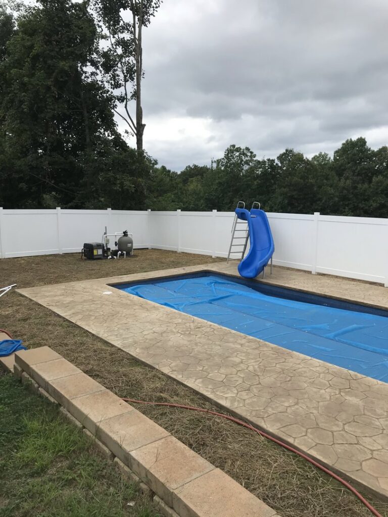 A white vinyl privacy fence enclosing a pool area with a blue slide by The Fence Dr. in Scranton, PA.