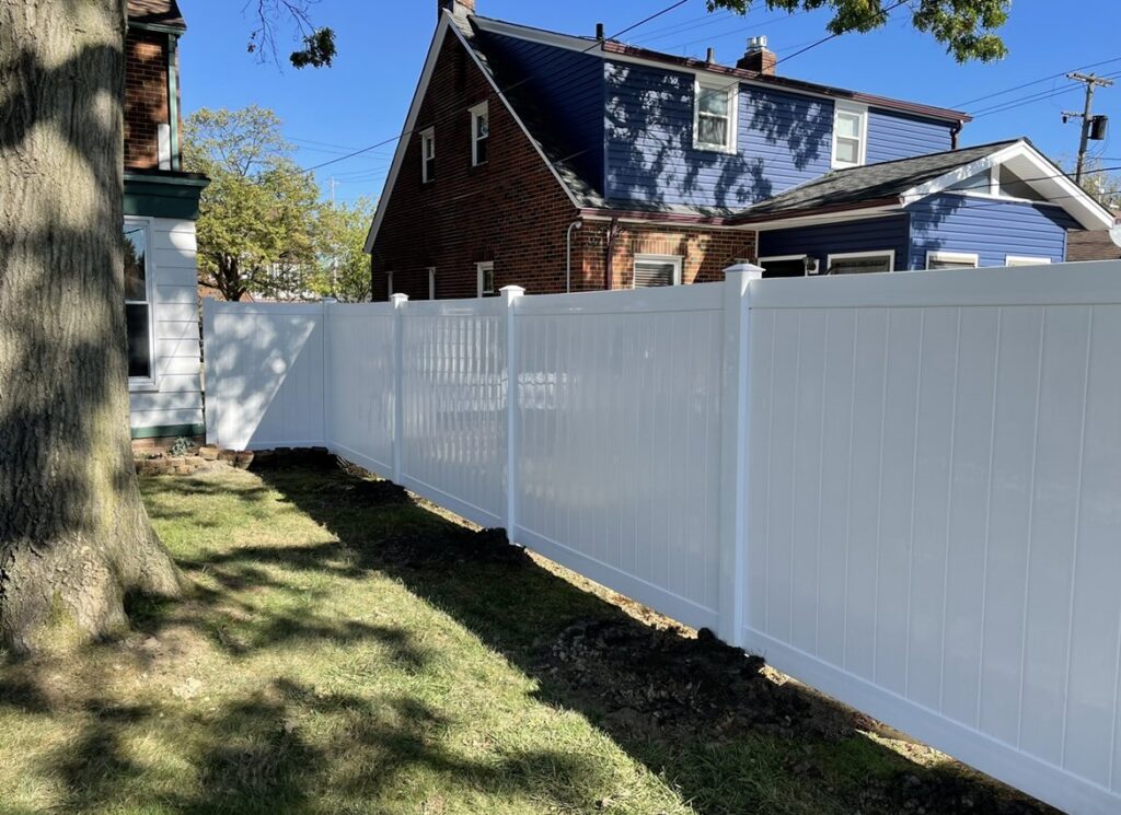 A white vinyl privacy fence installed along a residential property line by Affordable Fencing in Parma, OH.