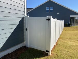 A clean white vinyl privacy fence with a gate installed in a residential backyard by Endurance Fence Solutions, LLC in Holly Springs, NC