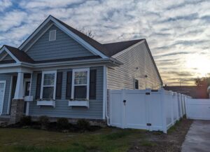 A white vinyl privacy fence installed along the side of a residential home by Fast Fences LLC in Northfolk, VA.