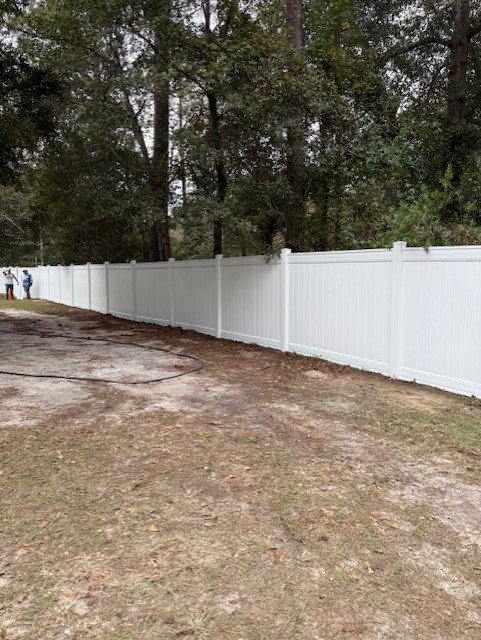 A long white vinyl privacy fence installed along a residential property line by JBunlimitedfencingllc in Savannah, GA.