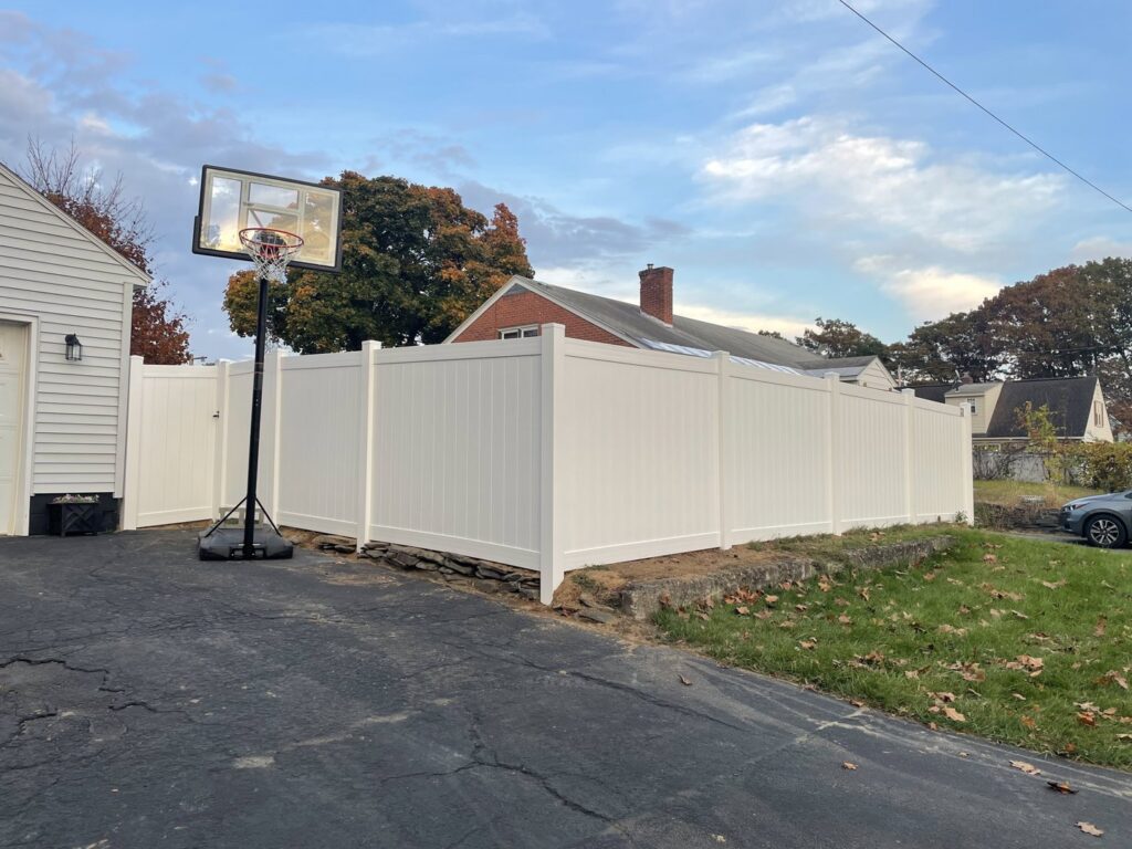 A white vinyl privacy fence installed in a residential backyard, offering seclusion from Vision One Construction LLC in Schenectady, NY