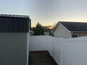 A section of white vinyl privacy fence installed next to a shed by Fayetteville Fence Pros in Fayetteville, NC.