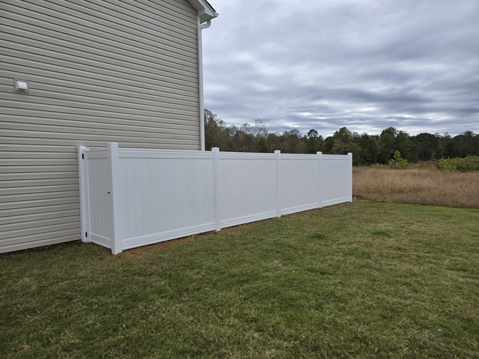 A white vinyl privacy fence section installed next to a house by Outsiders Fencing in Greensboro, NC.