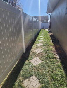 A pristine white vinyl privacy fence installed along a residential side yard by Discount Fence Supply in Great Falls, SC.