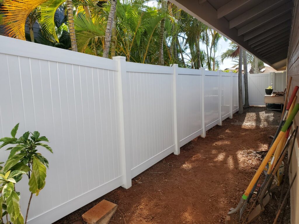 A white vinyl privacy fence installed along a narrow side yard by Redmond Valleywide - Hawaii's Fence Company in Kapolei, HI