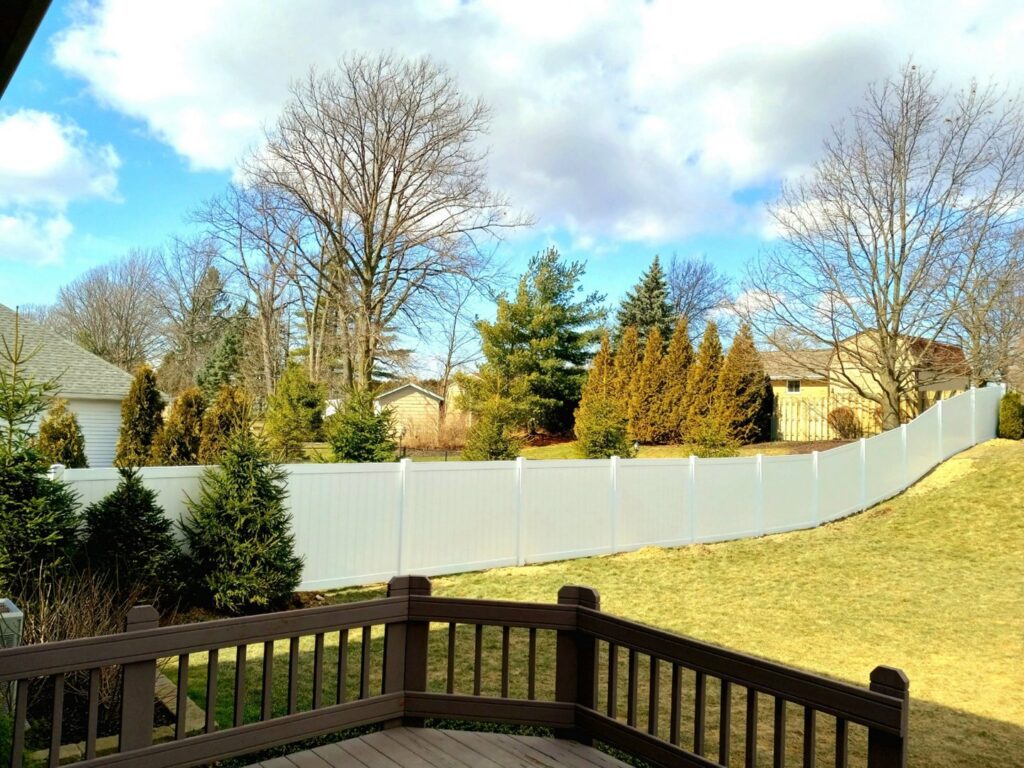 A white vinyl privacy fence installed on a sloped backyard property by Affordable Fencing in Parma, OH.