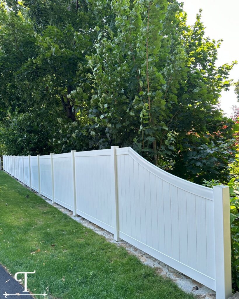 A long white vinyl privacy fence with a decorative curved top, installed by Teto's Fence Installation in Bridgeport, CT.
