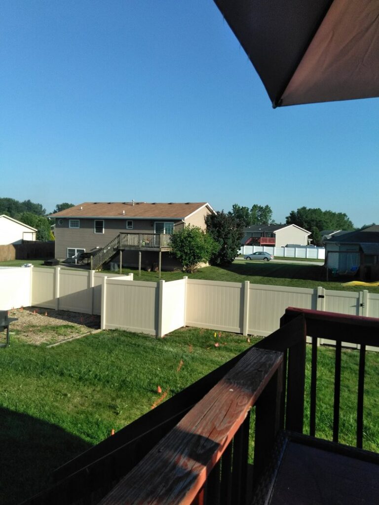 A white vinyl privacy fence under construction in a residential backyard by AmeriDream Fence & Deck in Joliet, IL.