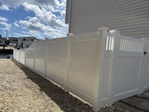A pristine white vinyl privacy fence installed along a waterfront property by MAC Fencing LLC in Toms River, NJ