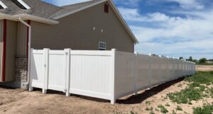A white vinyl privacy fence with a gate installed next to a house by 208 Fence and Gate in Idaho Falls, ID.