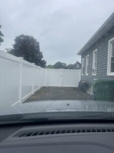A white vinyl privacy fence with a gate, installed for a residential property by Brodeur-Campbell Fence Co. in Springfield, MA.