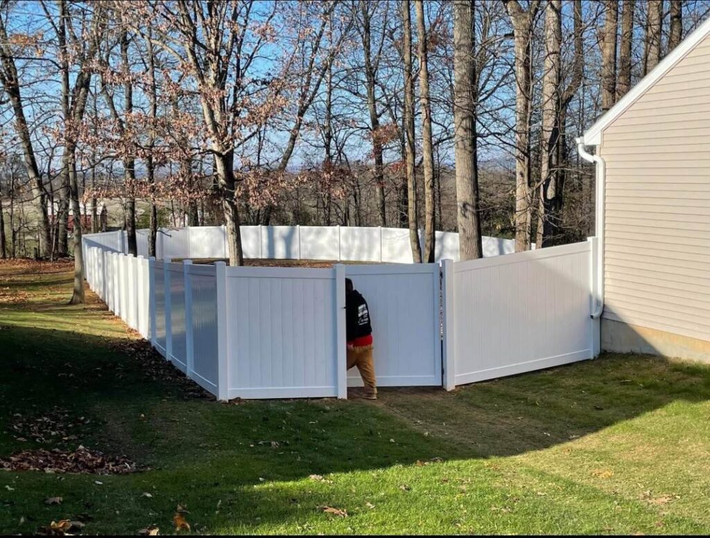 A white vinyl privacy fence with an open gate, showing a person, installed by DZS Fencing, LLC in Red Lion, PA.