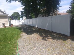 A long white vinyl privacy fence with a matching gate, installed by Reilly Fence Inc in Cranston, RI.