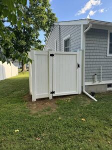 White vinyl privacy fence with a gate installed next to a house by Select Fence & Guardrail in North Haven, CT.