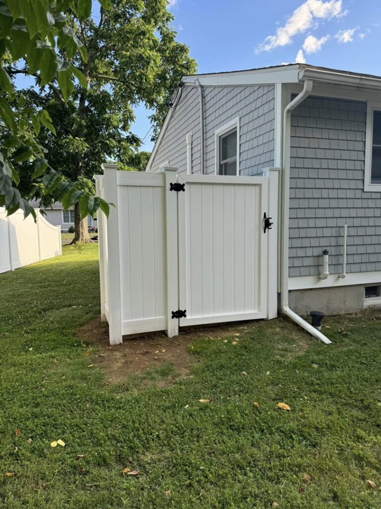 White vinyl privacy fence with a gate installed next to a house by Select Fence & Guardrail in North Haven, CT.