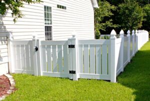 A white vinyl privacy fence with a gate installed next to a house by Sumter Fence Company in South Sumter, SC.