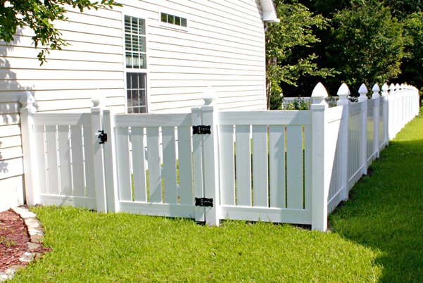 A white vinyl privacy fence with a gate installed next to a house by Sumter Fence Company in South Sumter, SC.
