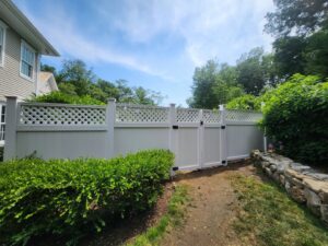 A white vinyl privacy fence with a lattice top and double gates, installed by H&M Fence, LLC in Norwalk, CT.