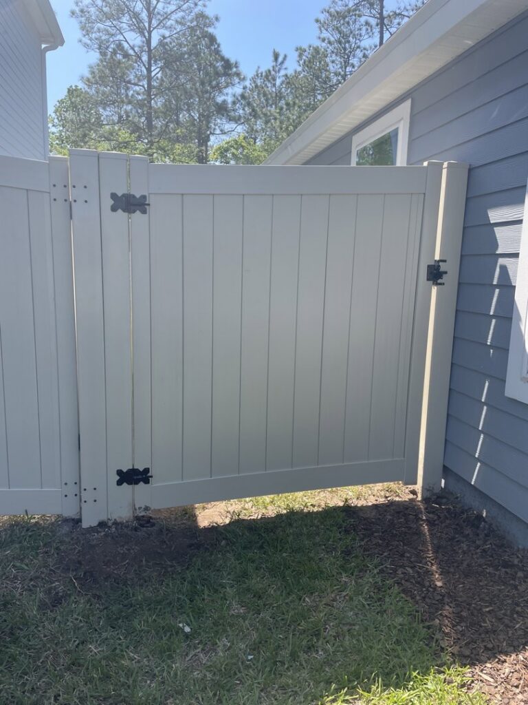 A newly installed white vinyl privacy gate next to a residential home by R&R Fence Services in Jacksonville, FL.