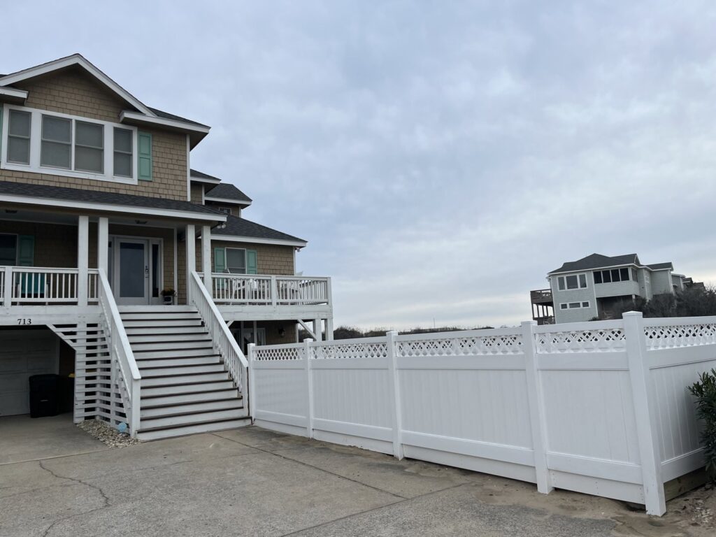 A white vinyl privacy fence with a decorative lattice top installed by Sea Level Fence in Harbinger, NC