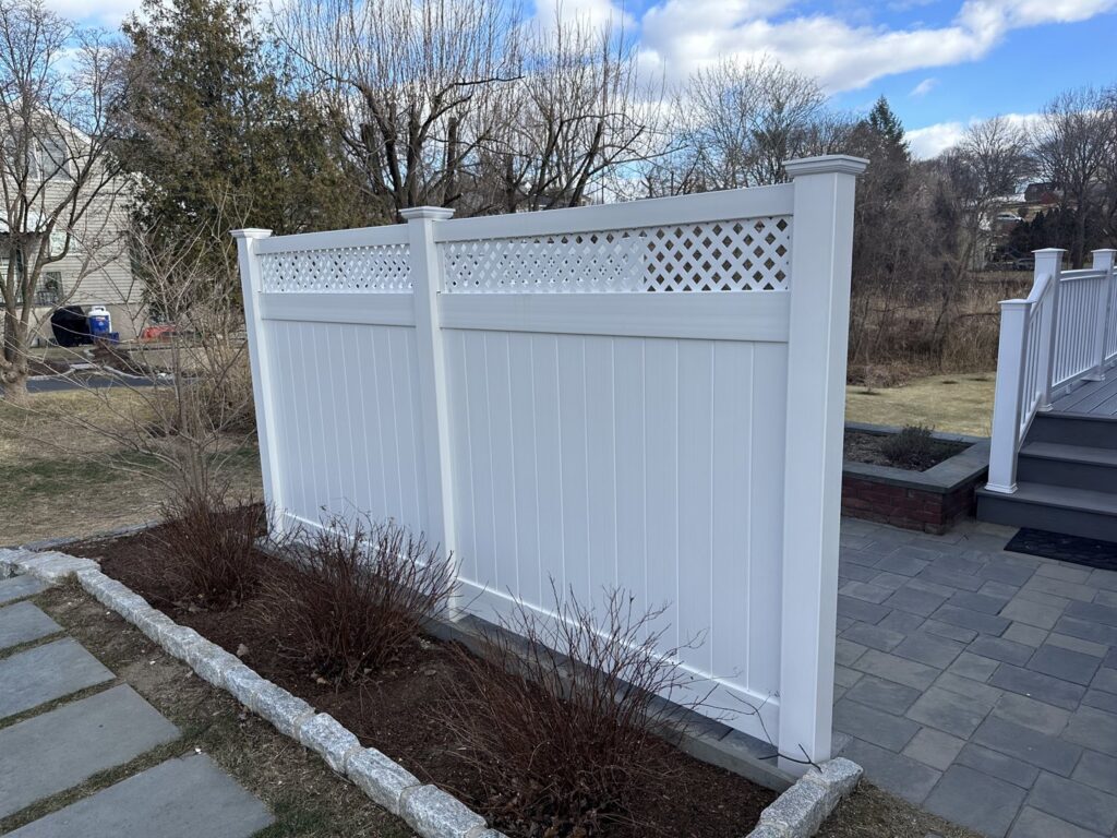 A white vinyl privacy screen fence with a lattice top installed next to a patio by Quality Fence Inc. in Peekskill, NY