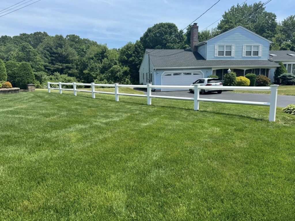 A white vinyl ranch-style fence installed in a residential front yard by Select Fence & Guardrail in North Haven, CT.