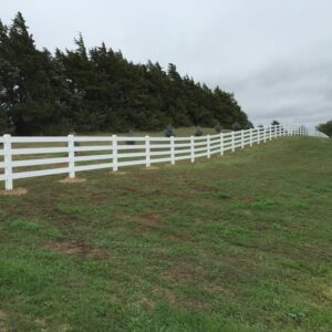 A white vinyl ranch-style fence installed in a rural landscape by Schumacher Fencing, LLC in Columbus, NE.