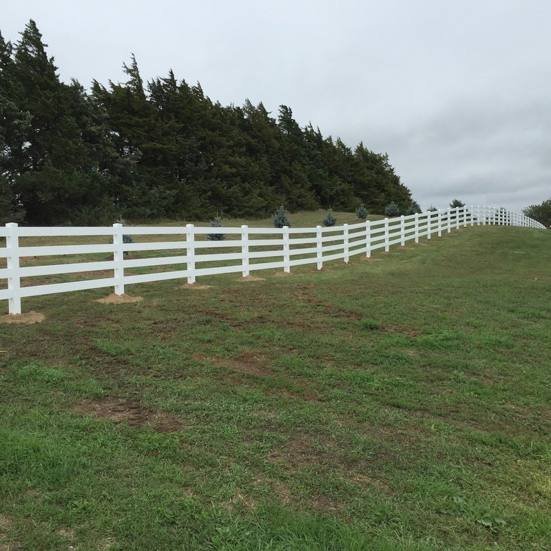 A white vinyl ranch-style fence installed in a rural landscape by Schumacher Fencing, LLC in Columbus, NE.