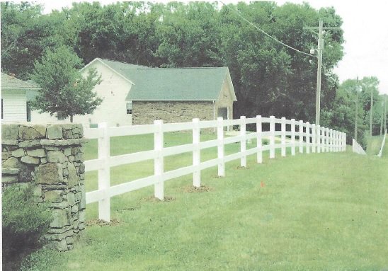 A white vinyl ranch-style fence with a decorative stone pillar installed by James Fencing LLC in Columbia, MO.
