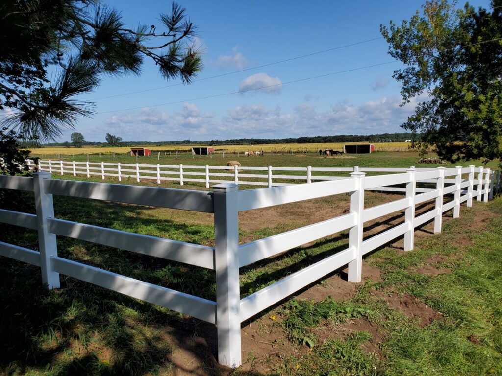 A durable white vinyl ranch-style fence installed in a rural landscape by Top Notch Fence in East Bethel, MN