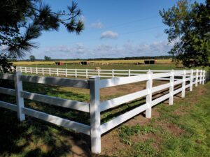 A durable white vinyl ranch-style fence installed in a rural landscape by Top Notch Fence in East Bethel, MN