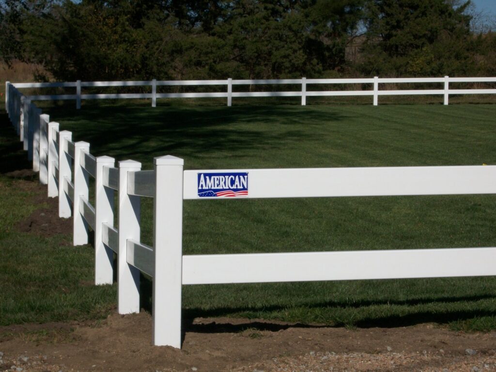 A white vinyl ranch-style fence installed in a grassy area by American Fence Company of Norfolk in Grand Island, NE.