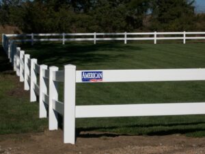 A white vinyl ranch-style fence installed in a grassy area by American Fence Company of Norfolk in Grand Island, NE.