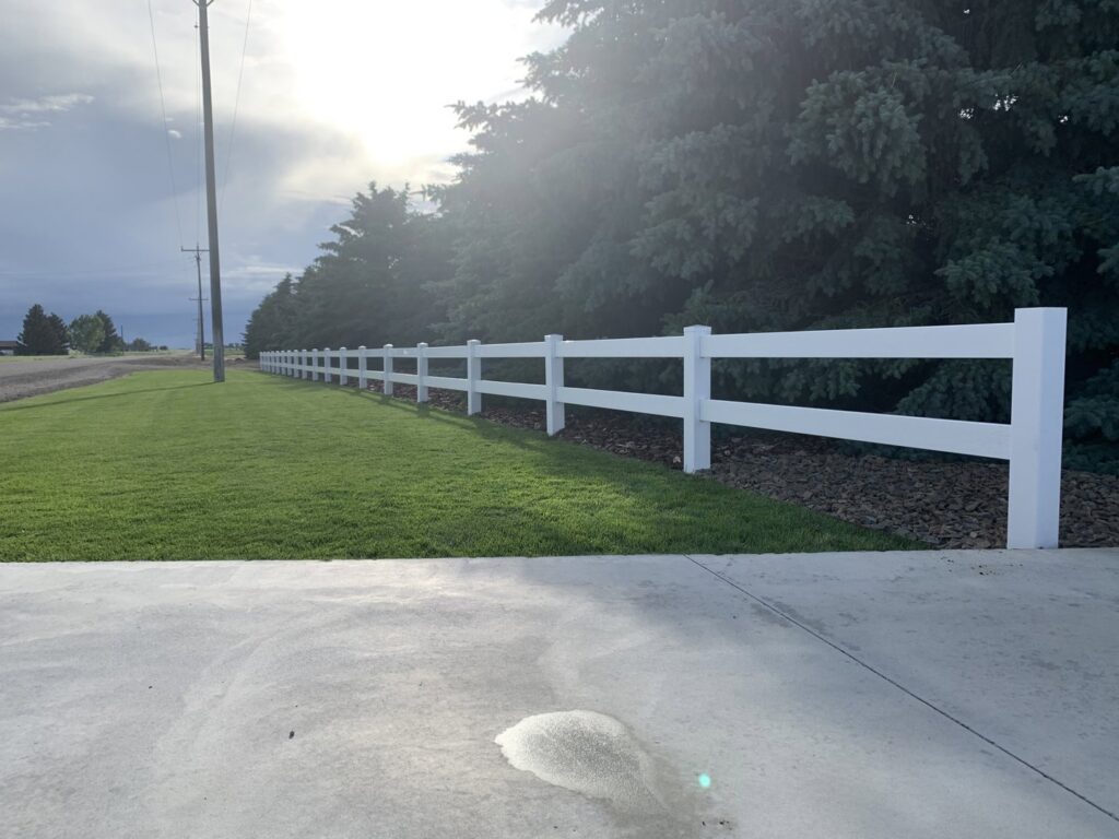 A long white vinyl ranch-style fence installed along a property line by Idaho Falls Fencing in Idaho Falls, ID.