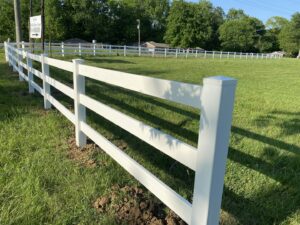 A newly installed white vinyl ranch-style fence in a grassy field by Alabama's Fencing in Huntsville, AL.