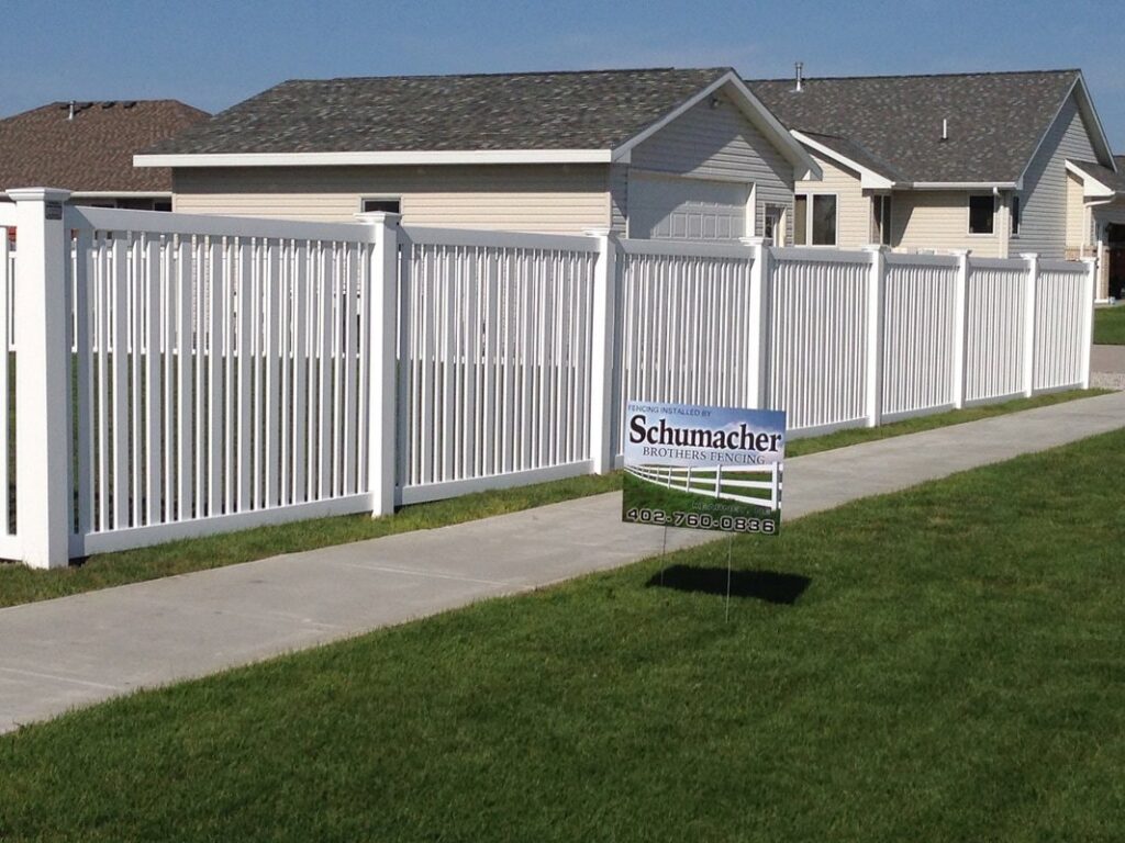 A white vinyl semi-privacy fence installed along a residential sidewalk by Schumacher Fencing, LLC in Columbus, NE.