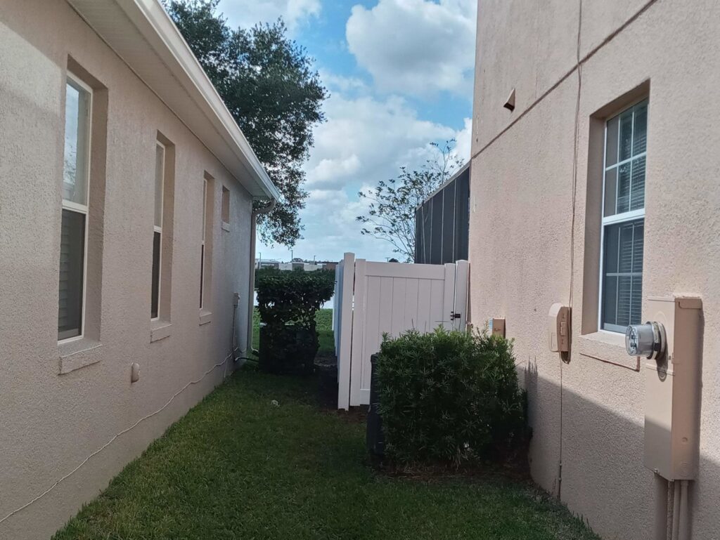 A white vinyl gate installed in a side yard between two houses by Florida Professional Fence LLC in Altamonte Springs, FL.