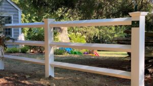 A clean white vinyl split rail fence installed in a residential yard by Flanagan Fencing in Brookfield, CT.