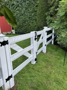 A white wood and wire mesh fence with a gate installed in a residential yard by Building Fences in Westchester NY.