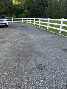 A long white wood and wire mesh fence installed along a gravel driveway by Building Fences in Westchester NY.