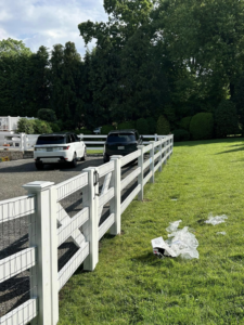 A white wood and wire mesh fence separating a gravel driveway from a lawn by Building Fences in Westchester NY.