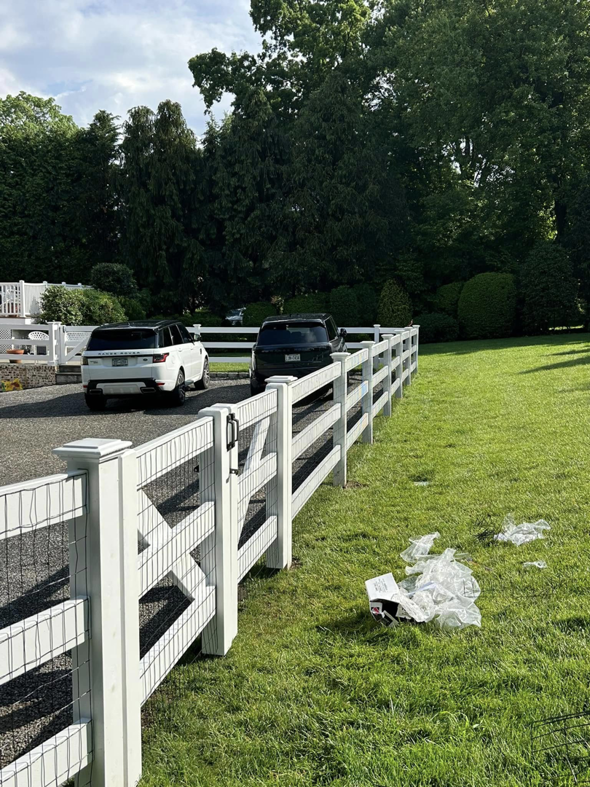 A white wood and wire mesh fence separating a gravel driveway from a lawn by Building Fences in Westchester NY.