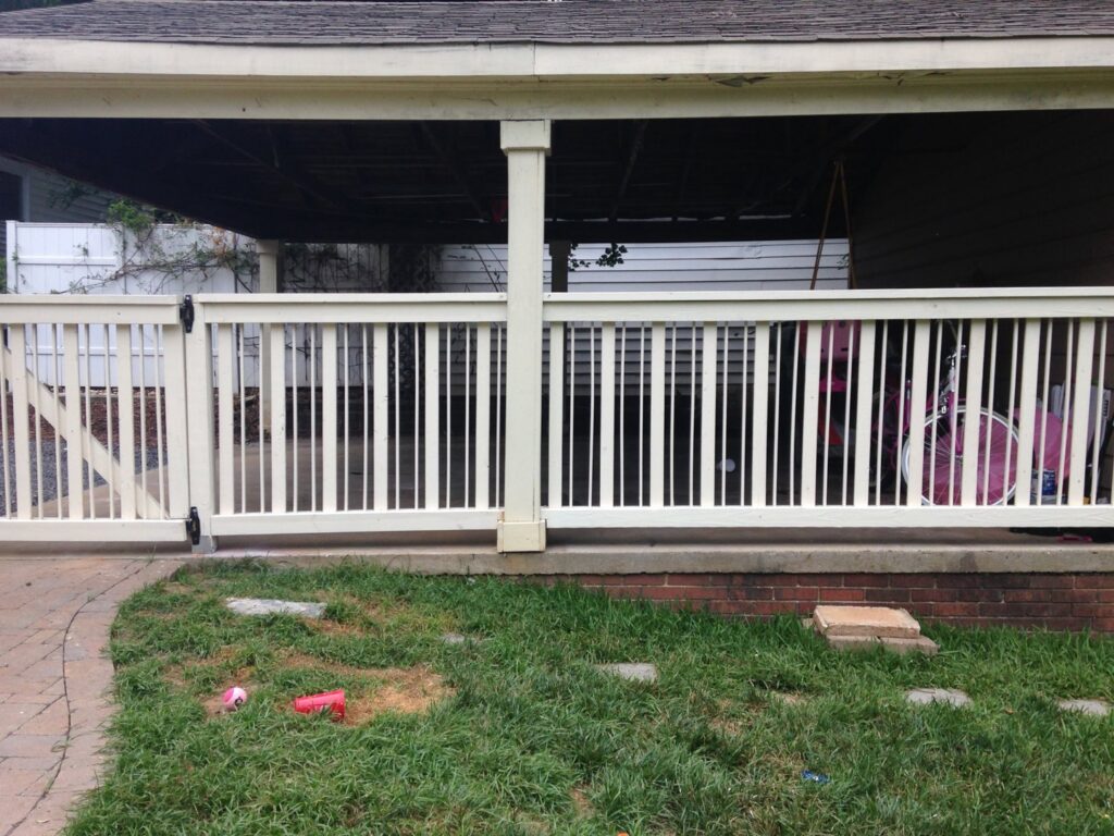 A white wooden railing and gate enclosing an area under a carport, installed by Timber Fencing in Charlotte, NC.